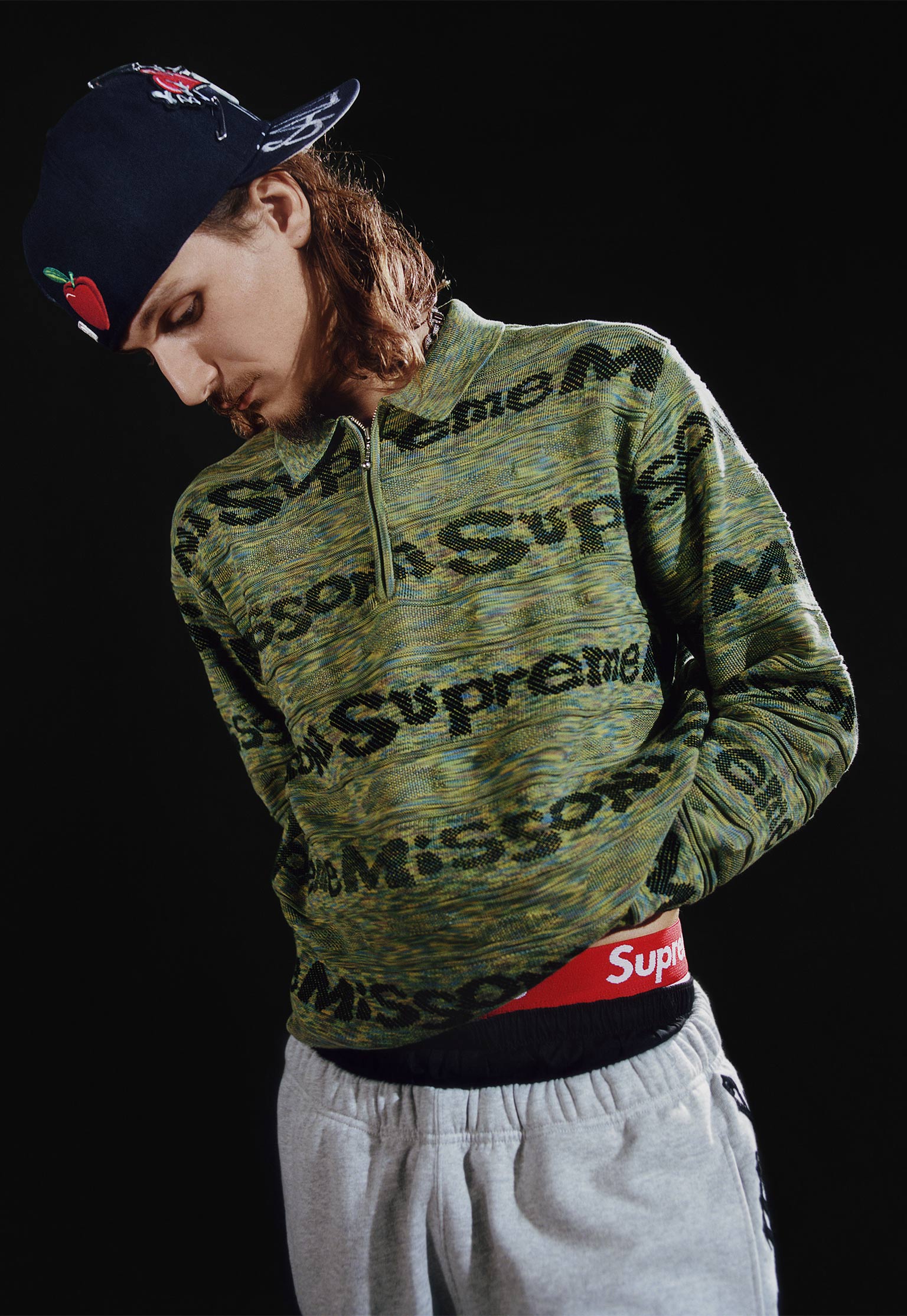 The model is wearing a zip-neck sweater with an embroidered texture 
