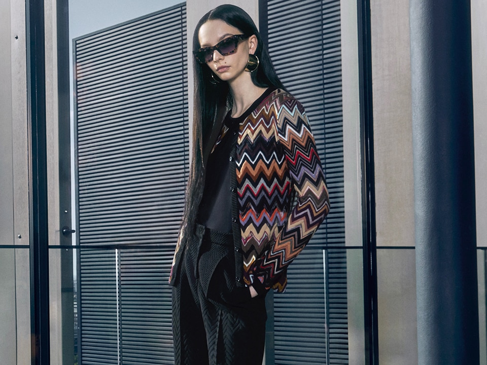 A model is wearing a total black outfits with a multicoloured zig zag cardigan from the Fall Winter 2023 collection