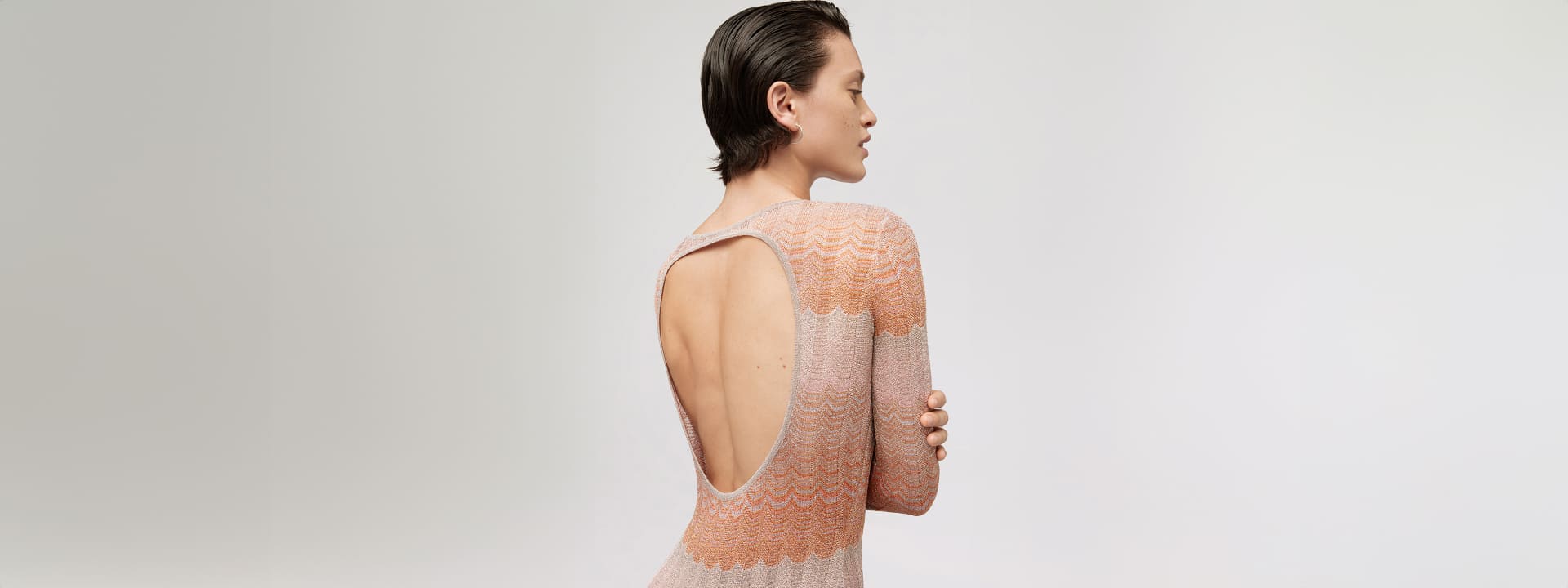 A model is wearing a long siren dress with an hole on the back