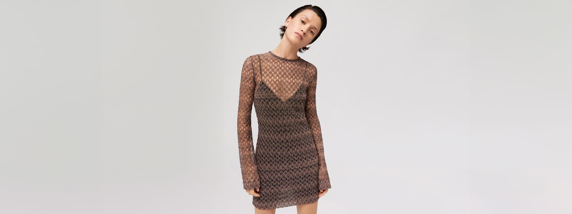 A woman is wearing a net dress in brown tones