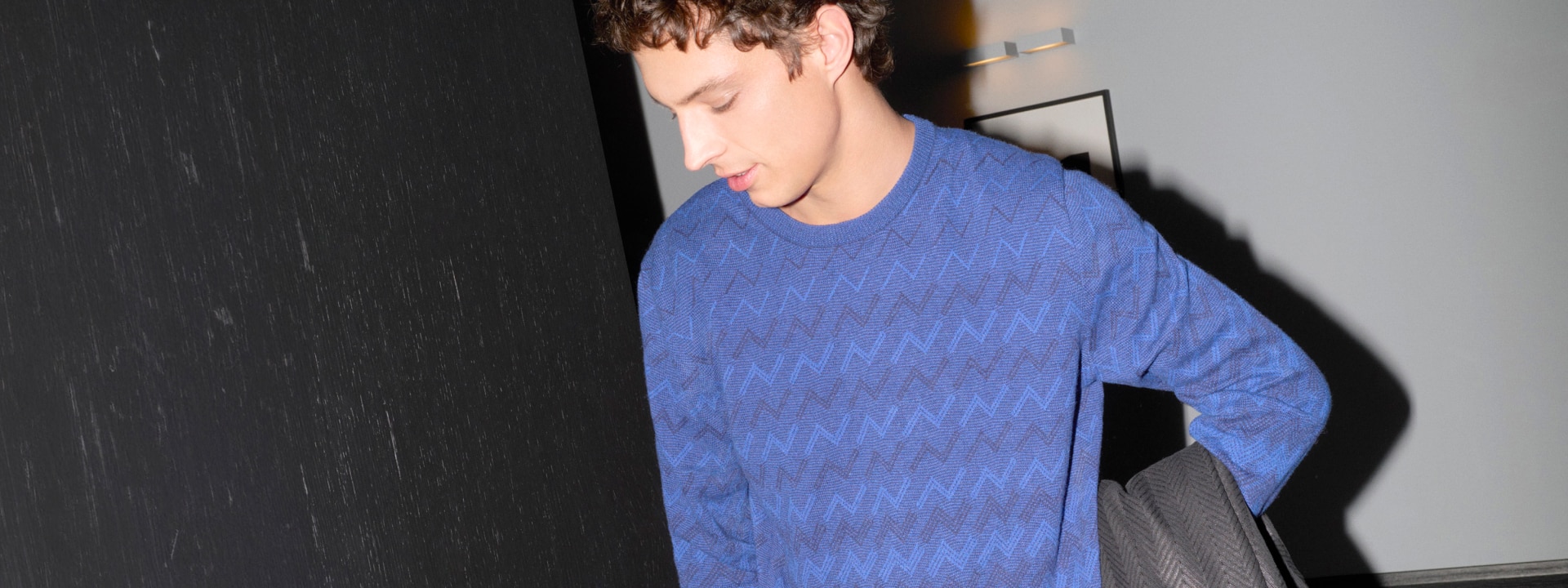 A model is wearing a blue zig zag jumper from the Spring Summer 2024 collection