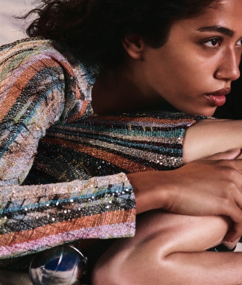 A model is wearing a sparkling jacket in dark tones