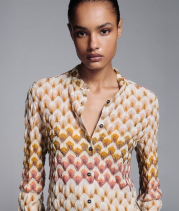A model is wearing a sparkling jacket in dark tones