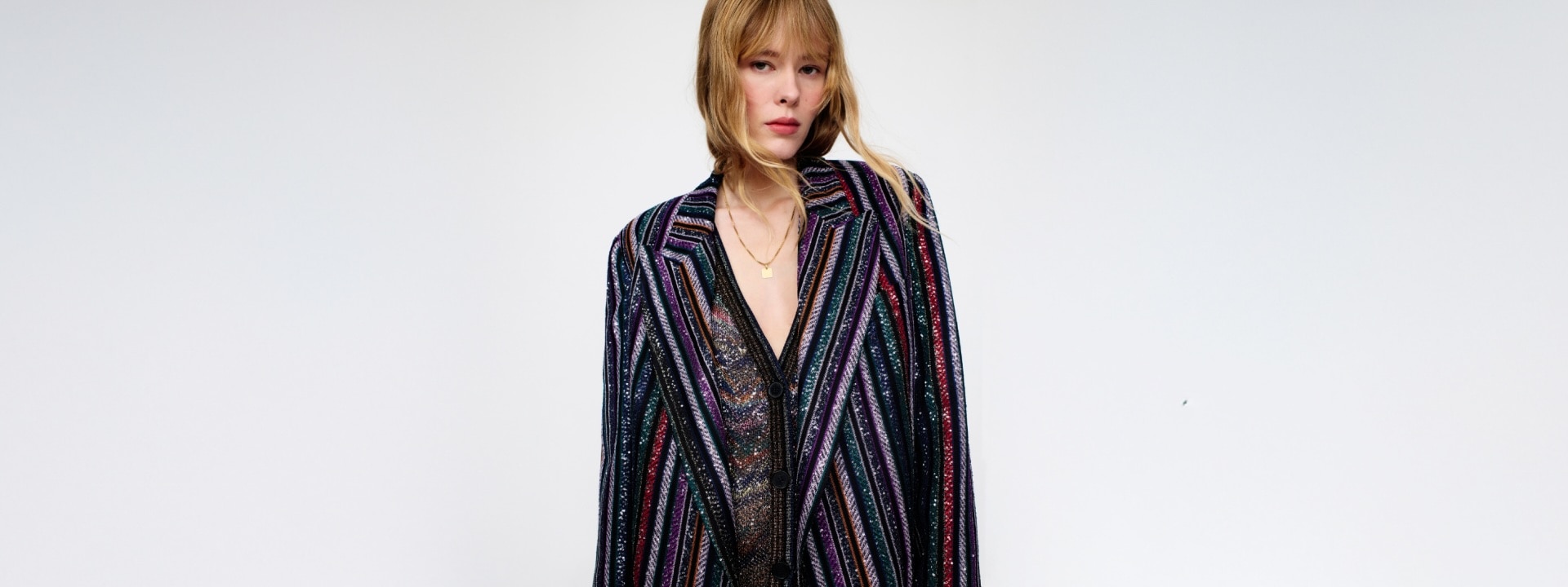 A model is wearing a sparkling jacket in dark tones