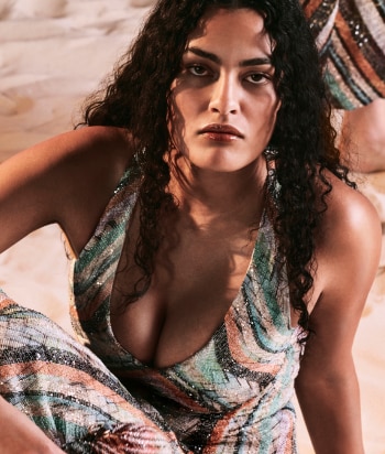 A model is wearing a two pieces jumpsuits, with a sleeveless top and a pair of long trousers, in brown striped tones