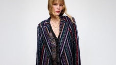 A model is wearing a sparkling jacket in dark tones