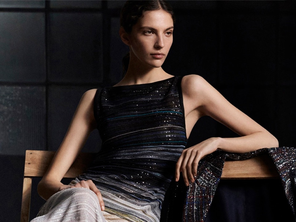 A model is wearing a blouse in black and sheer horizontal striped pattern. 