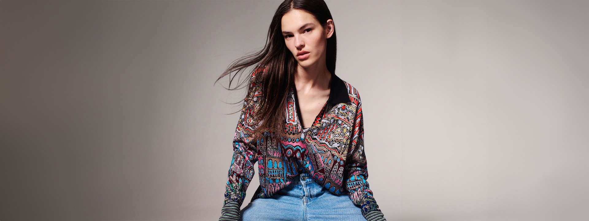 A model is wearing a short cardigan with colorful patchwork