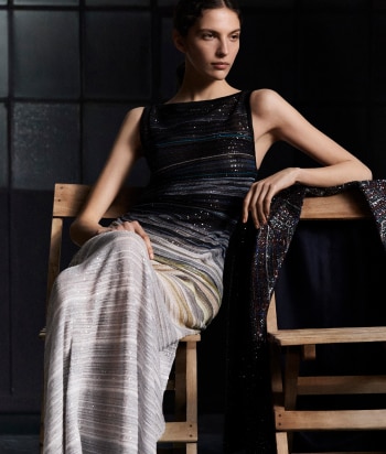 A model is wearing a two pieces jumpsuits, with a sleeveless top and a pair of long trousers, in brown striped tones