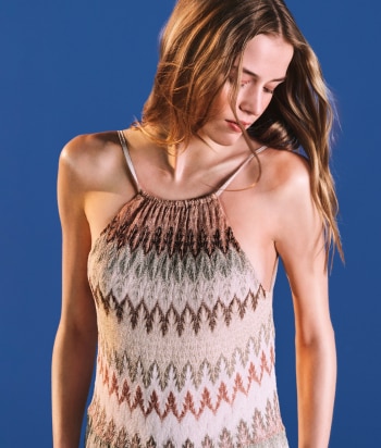 A model is wearing a strapless short dress in brown tones