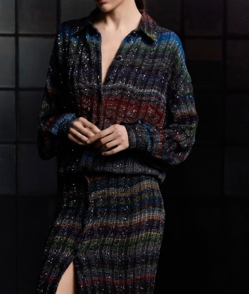 A model is wearing a sparkling jacket in dark tones