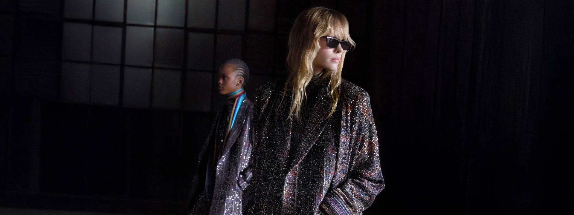 A model is wearing a sleeveless dress with black and sheer horizontal striped pattern.