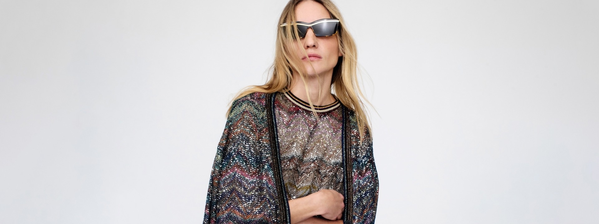 A model is wearing a multicoloured sparkling metallic knit sweater and cardigan with zigzag pattern.