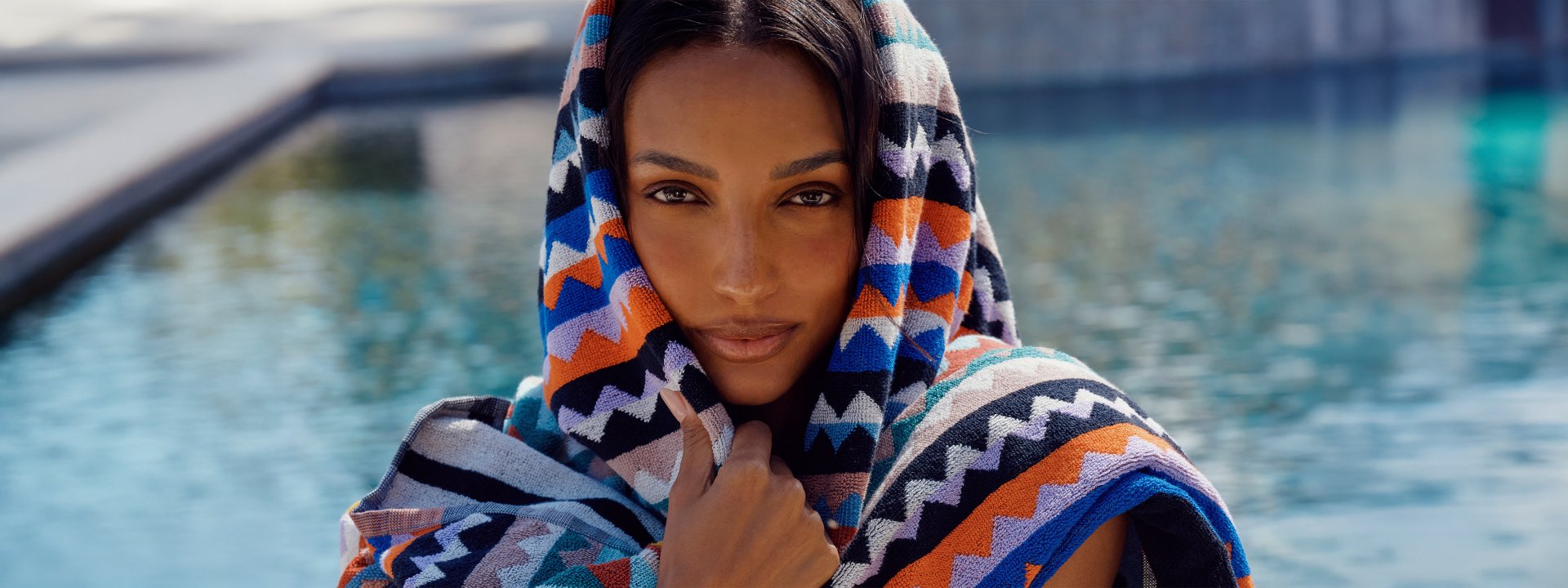A model is wearing a zig zag beach towel around her face