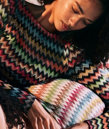 A model is wearing a two pieces jumpsuits, with a sleeveless top and a pair of long trousers, in brown striped tones