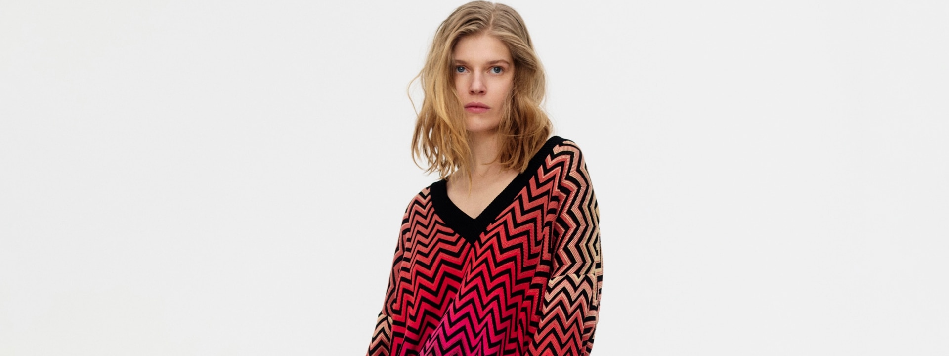 A woman is wearing a zig zag knitwear in pink tones