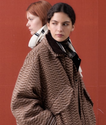 A model is wearing a two pieces jumpsuits, with a sleeveless top and a pair of long trousers, in brown striped tones