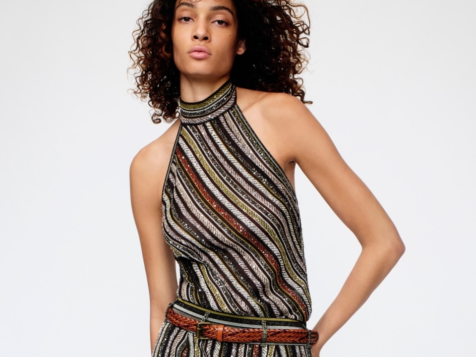 A model is wearing a strapless top and a pair of trousers, both in dark tones