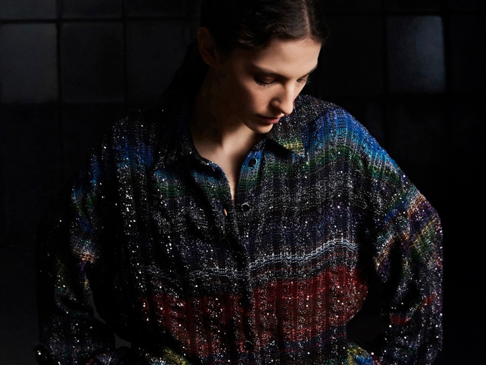 A model is wearing a blouse in black and sheer horizontal striped pattern. 